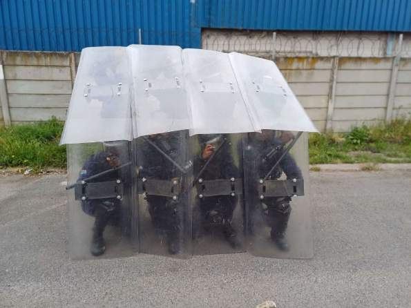 Officers in a kneeling riot shield formation