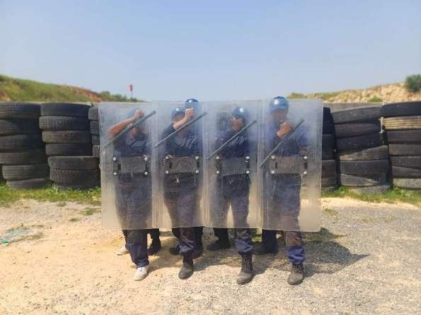 Line of officers in a standing riot shield formation